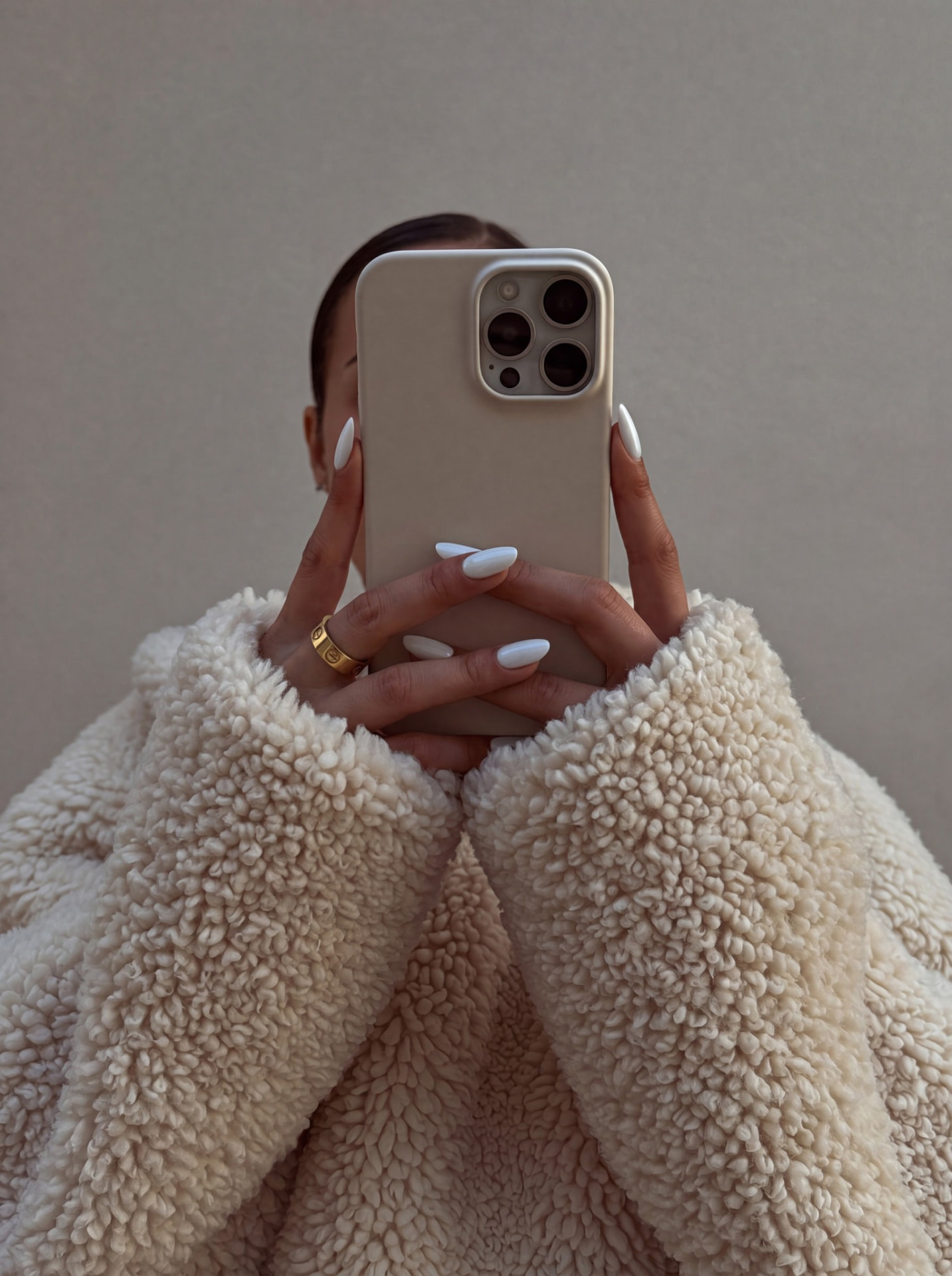 Woman in a cream sweater holding a smartphone