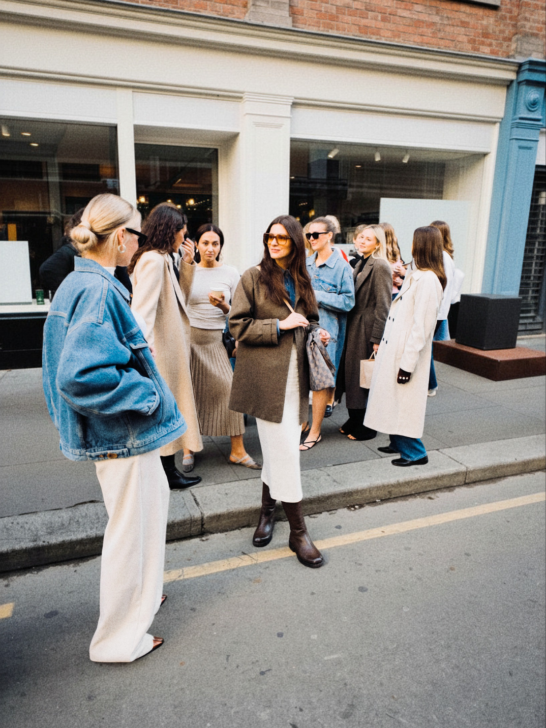 Group of women in autumn coats talking together on a city street outside a shopfront